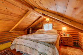 King size bed in bedroom loft at Honeymoon Hideout Cabin near Allenspark, Lyons, and Estes Park, Colorado.