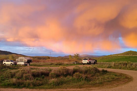 Sunset with orange clouds over cars and camping sites at Williams Fork Reservoir in Hot Sulphur Springs, Colorado.